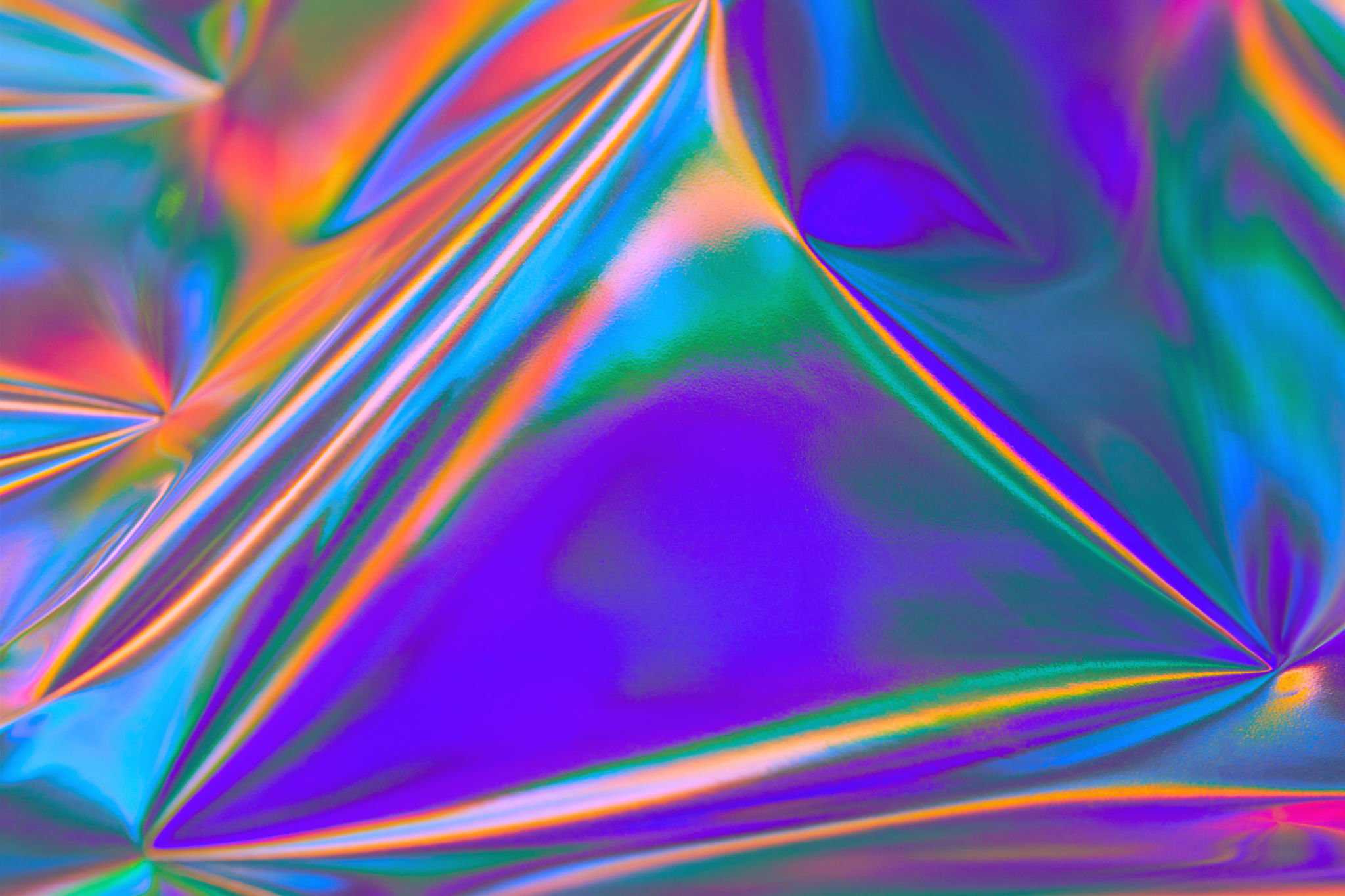 Abstract iridescent holographic texture with vivid blue, purple, green, orange, and pink light patterns.