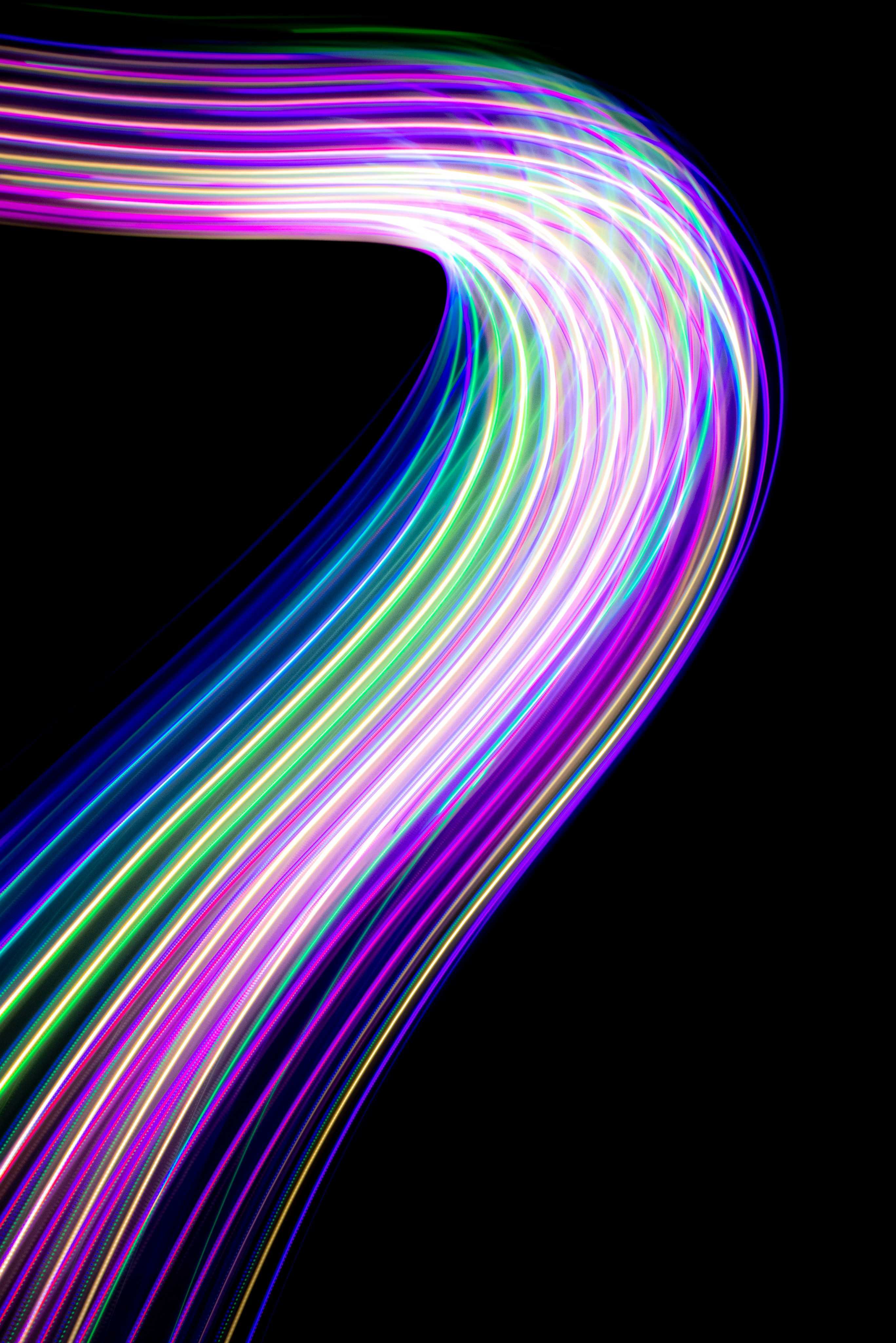 Abstract neon light trails curving against a black background